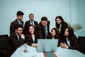 a diverse team of professionals collaborating around a laptop in a modern office setting. 26834970